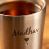 Close-up of engraved name Madhav on stainless steel cup showing detailed etching